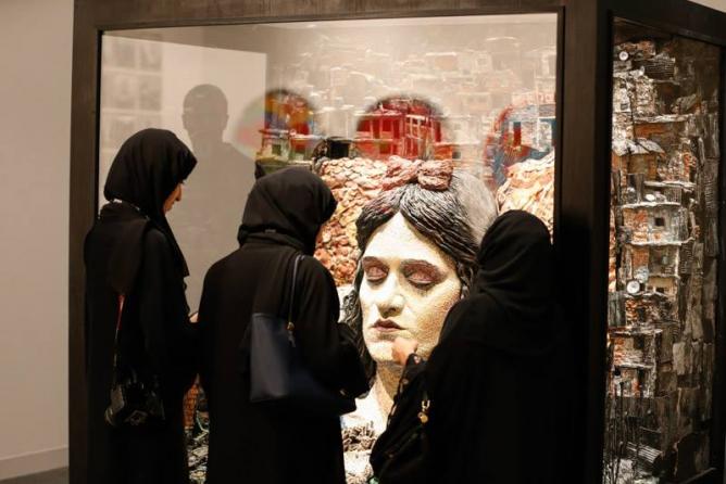 Abu Dhabi Art visitors studying art and one another.