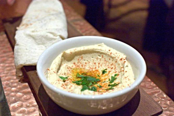 A bowl of hummus and house sweet bread sits on a wooden board at Zahav.