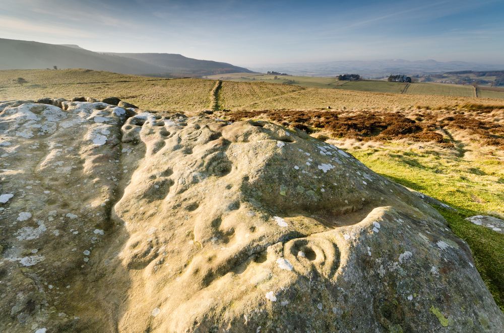 Prehistoric rock art / Ancient prehistoric cup and ring rock art is found on many stones at Lordenshaws in the Simonside Hills part of Northumberland National Park © Dave Head / Shutterstock