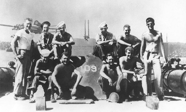 Lieutenant John F. Kennedy, USNR, (standing at right) with other crewmen on board PT-109, 1943. | © WikiCommons