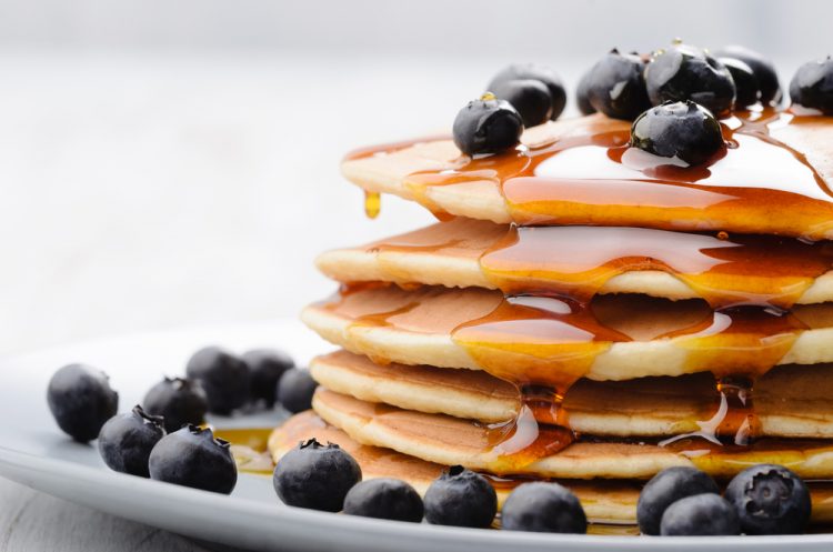 Delicious pancakes close up, with fresh blueberries and maple syrup
