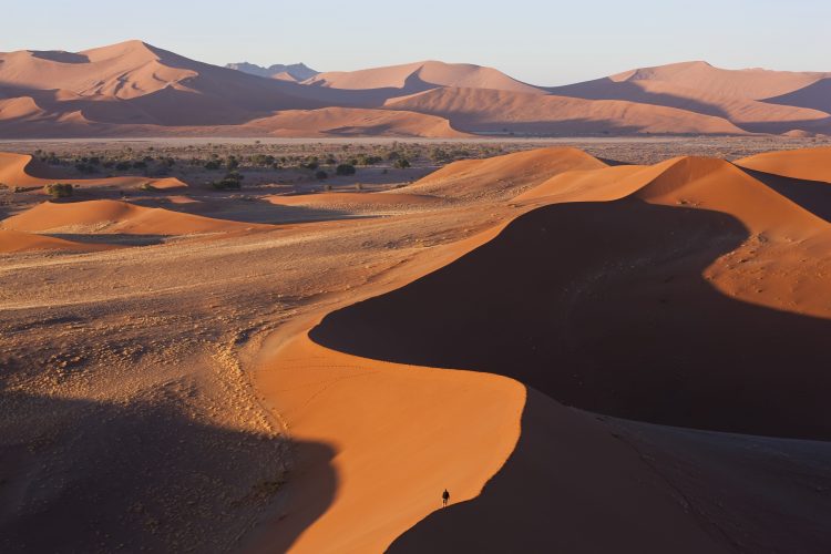 Man climbing sand dunes, Namib Naukluft National Park, Namibia