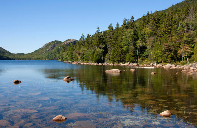 Acadia National Park, ME ? September 8, 2014: A line of trees is reflected in the clear waters of Jordan Pond, with the Bubbles