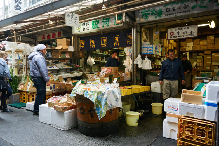 Merchants and customers stand in shops at Tsukiji/Toyosu fish market in Tokyo, Japan.