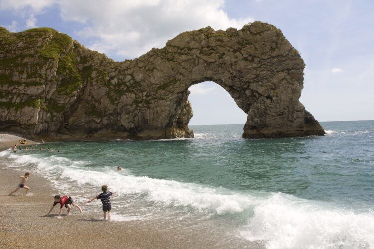 Holiday makers enjoy swimming on the beach at Durdle Door.