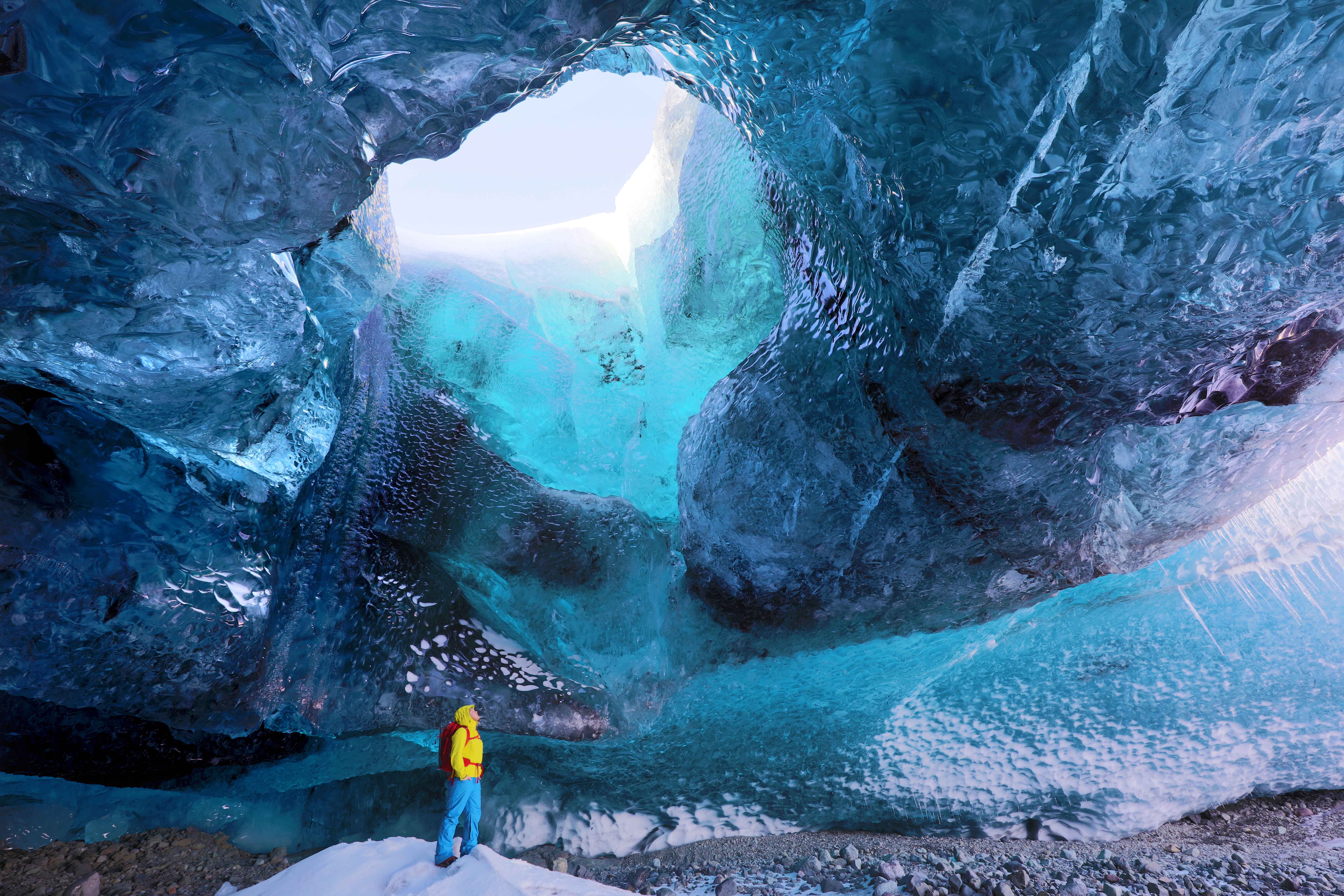 Inside ice cave under the Vatnajokull Glacier, with cave guide looking up to hole in cave roof, near Jokulsarlon, South Iceland