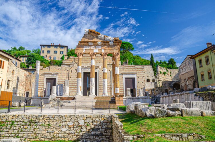 Capitolium of Brixia or Temple of Capitoline Triad or Tempio Capitolino ruins and Santuario Repubblicano, Brescia city historical centre, Cidneo Hill green trees background, Lombardy, Northern Italy
